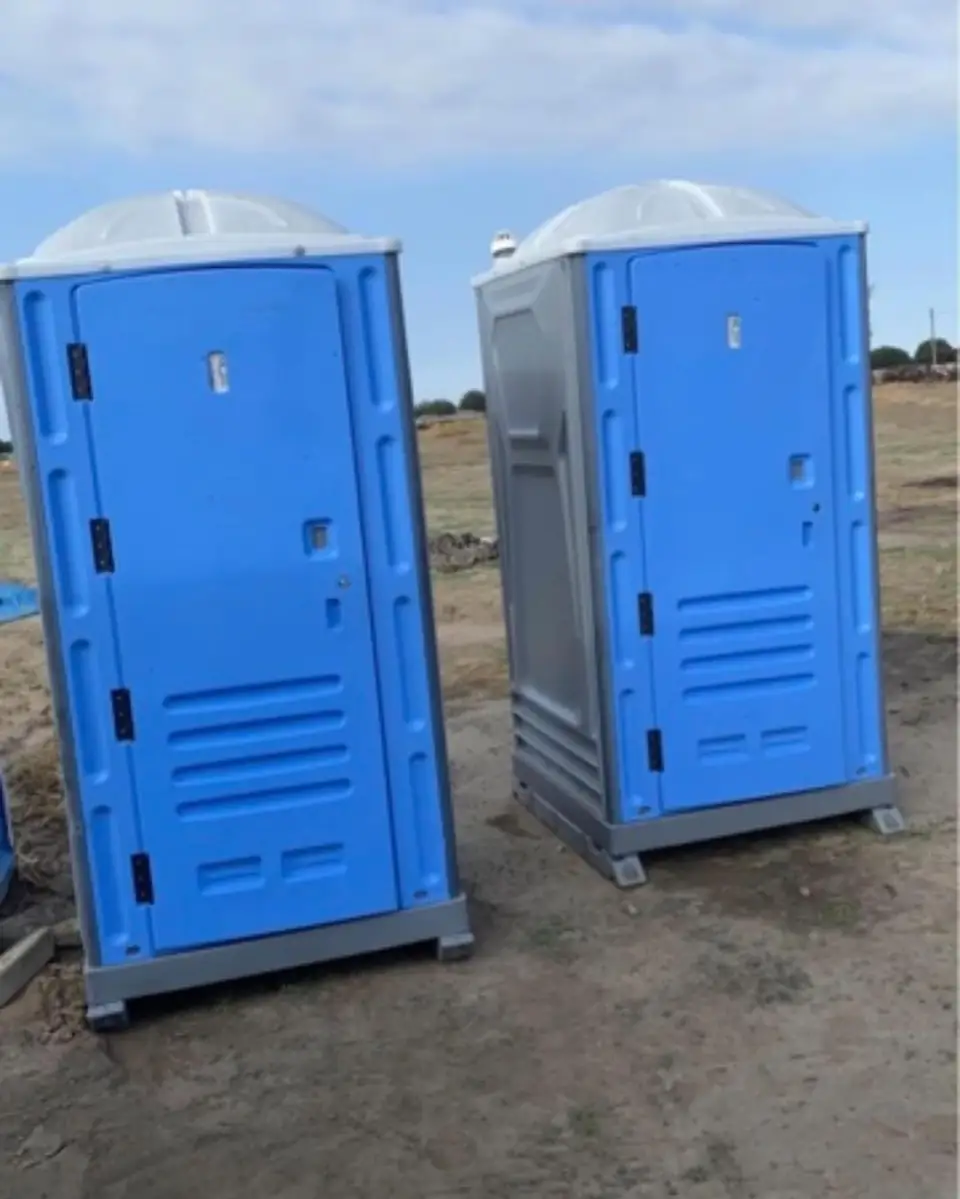 Two blue porta potties delivered to a dirt construction site