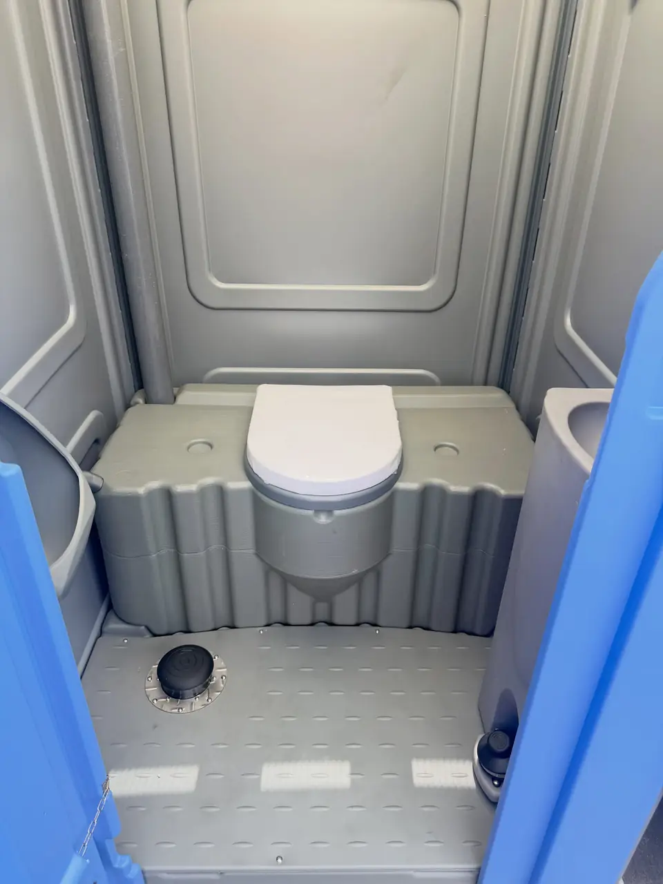 Clean grey interior of a flushing portable toilet