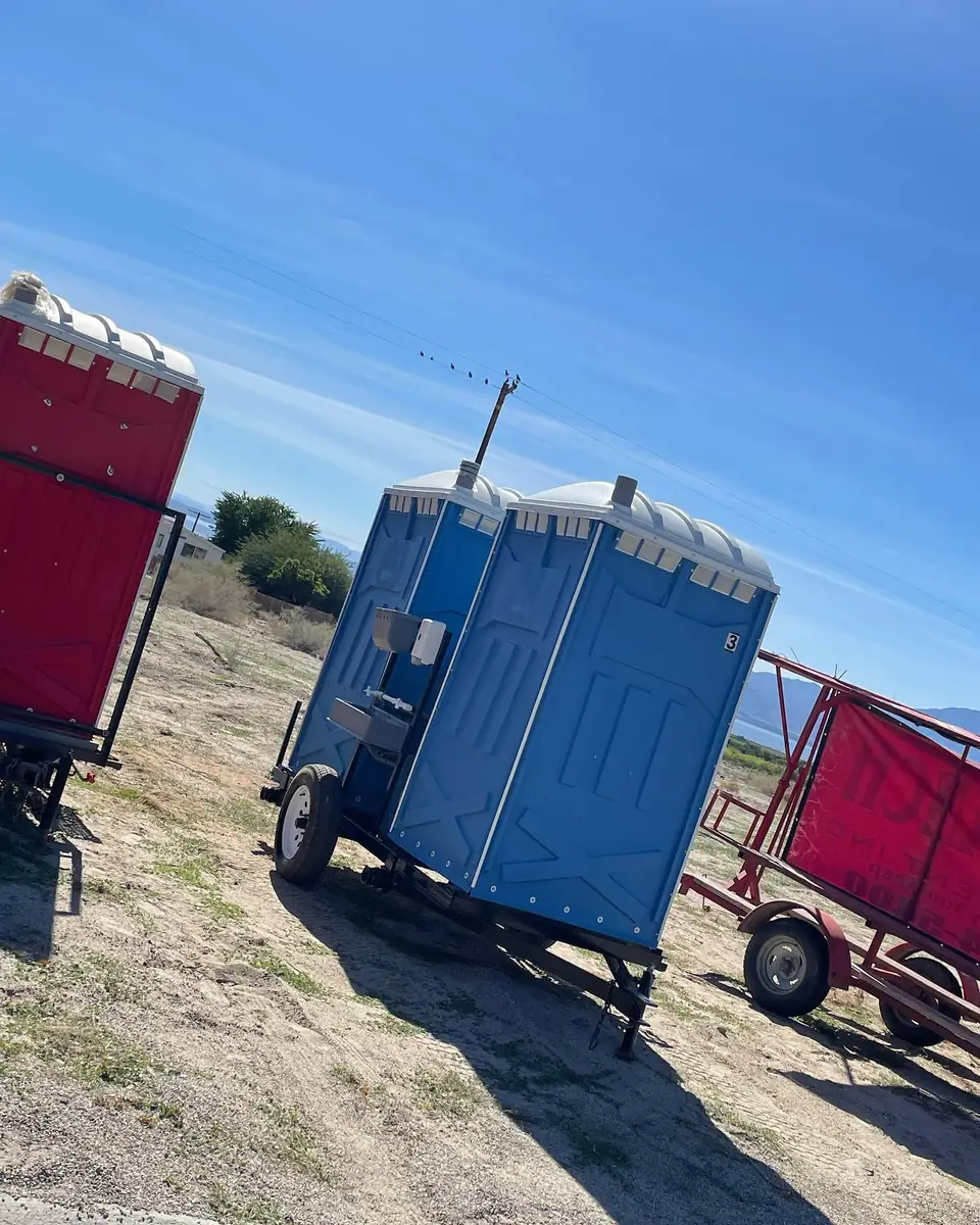 Portable toilets loaded on a trailer in a dirt yard
