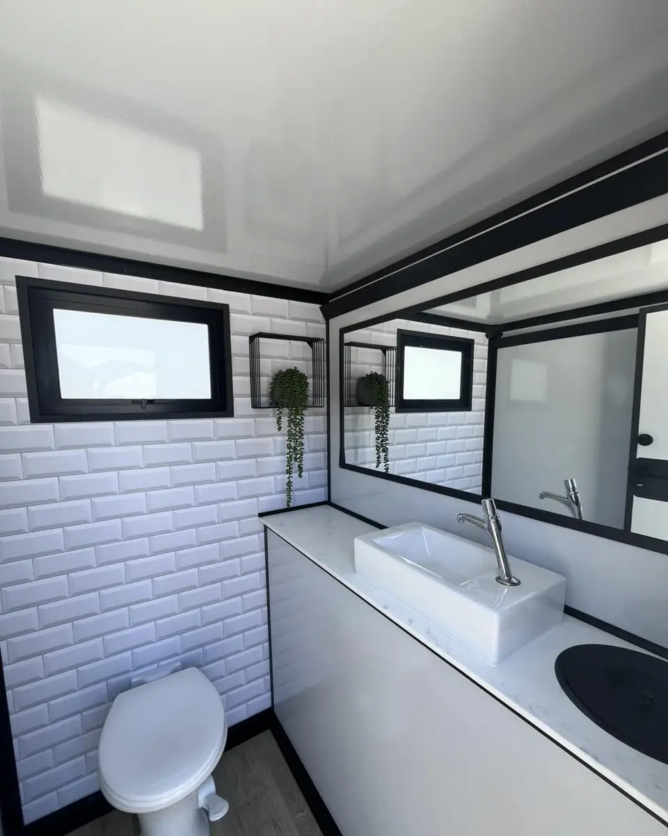 Restroom trailer interior with white tile wall, vanity sink and mirror