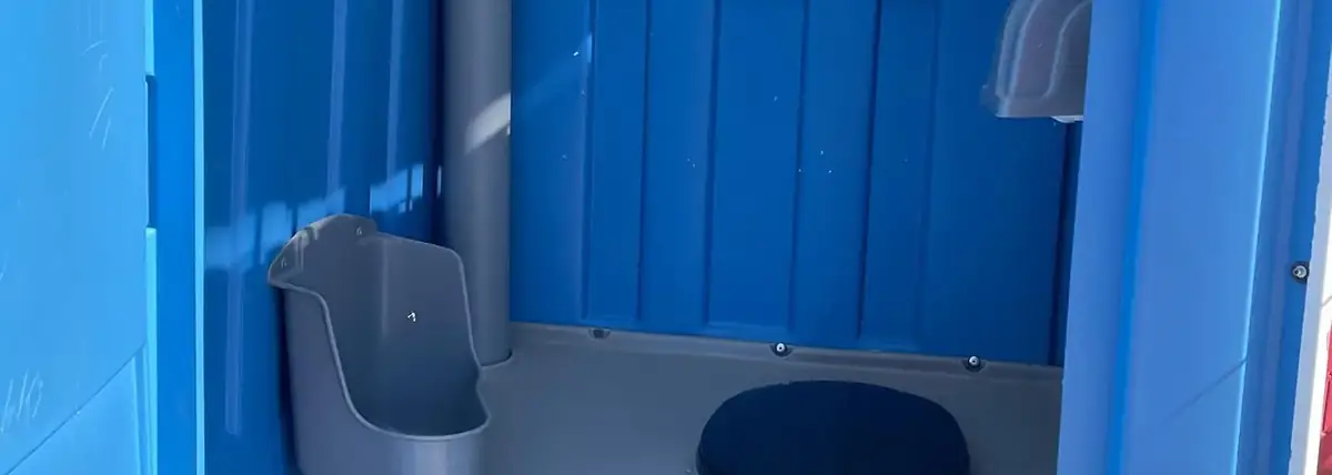 Inside a blue standard porta potty with toilet paper stocked