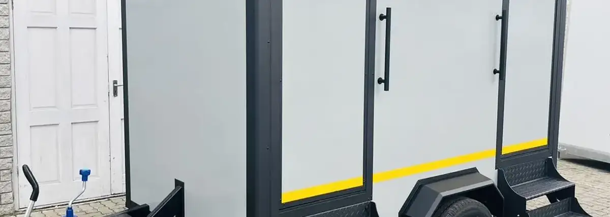 White two-stall restroom trailer with steps and separate doors for men and women